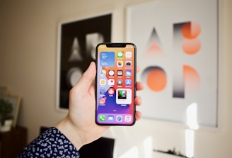 Close-up of hands holding a smartphone showing the jueganexo app interface with colorful game icons.